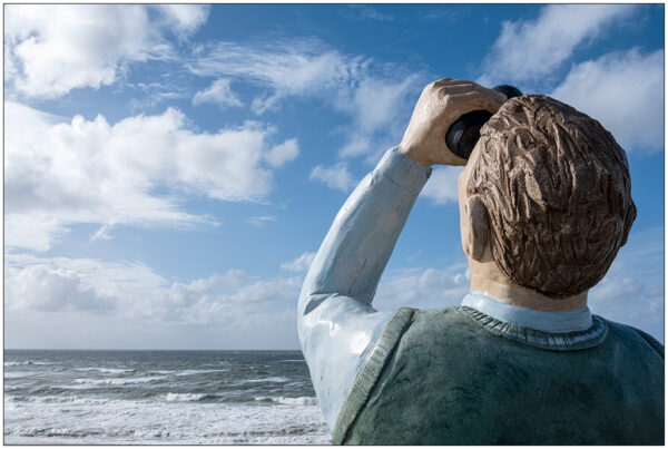 Fotografie Skulptur "Fernglasmann" von Christel Lechner in Wenningstedt auf Sylt. Blick in den Himmel über der Nordseee