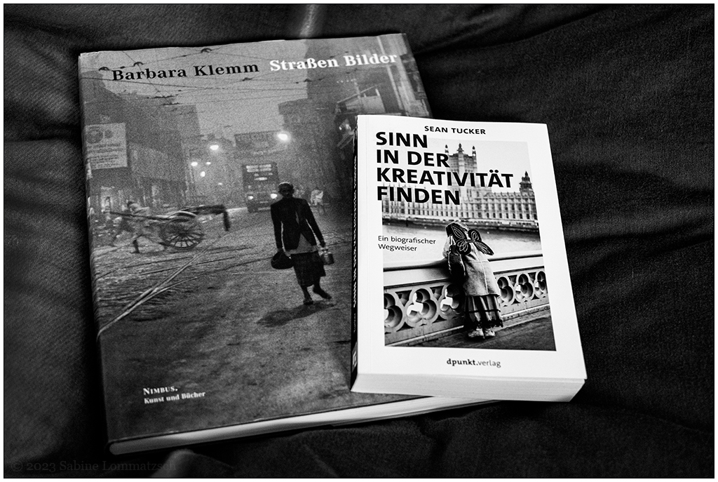 Fotografie in Schwarzweiß. Darauf zwei Bücher. Links ein Fotobildband von Barbara Klemm mit dem TItel "Straßen Bilder". Rechts ein Buch von Sean Tucker mit dem Titel "Sinn in der Kreativität finden".