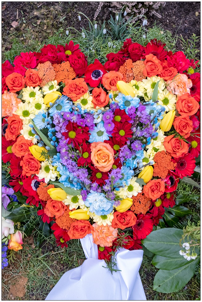 Draufsicht auf einen Kranz in Form eines Herzens. In bunten Farben aus vielen verschiedenen Blüten zusammengesetzt.