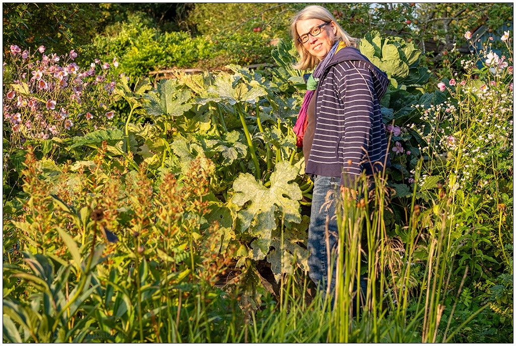 Frau steht inmitten von Pflanzen in einem Garten